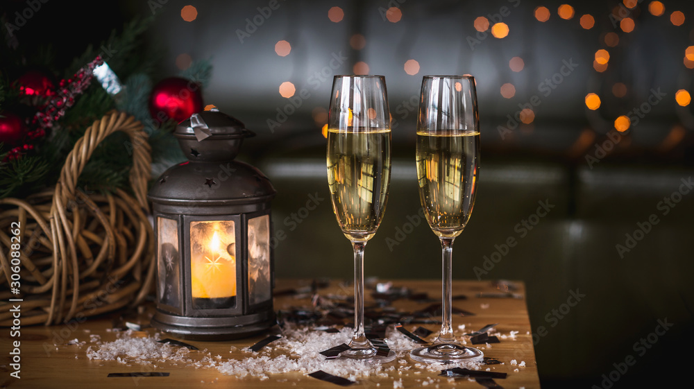 Two champagne glass on wooden loft table decorated christmas garland and lantern