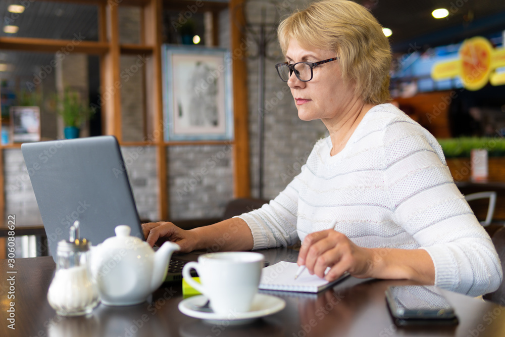 A woman with a laptop looks at a document in a cafe, office A woman with a laptop looks at a document in a cafe, office