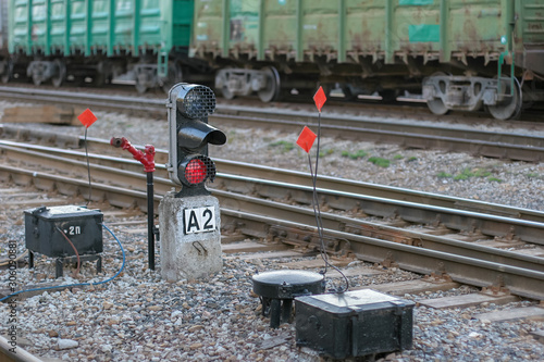 Foto Rails with freight cars in the background and a semaphore with a glowing red light in the foreground