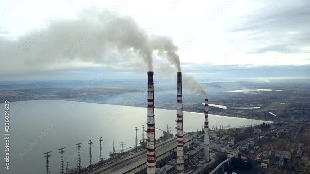 Aerial view of high chimney pipes with grey smoke from coal power plant. Production of electricity with fossil fuel. Aerial view of high chimney pipes with grey smoke from coal power plant. Production of electricity with fossil fuel.