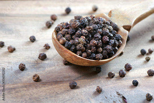 black pepper in a wooden spoon. close up