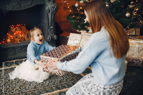 Beautiful mother in a blue sweater. Family with cristmas gifts. Little girl near christmas tree