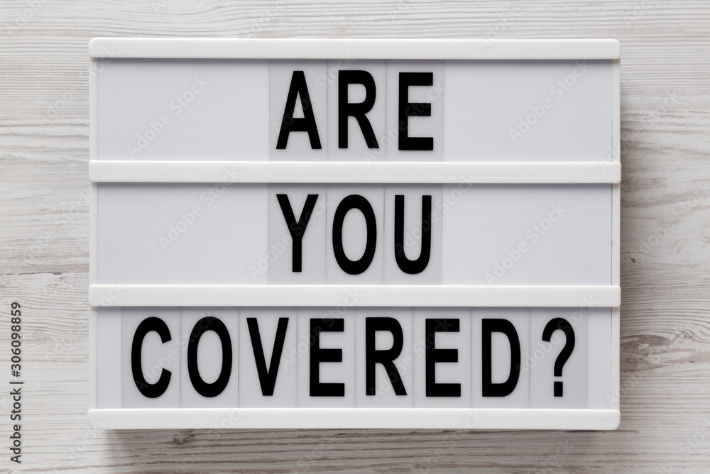 'Are you covered?' words on a lightbox on a white wooden background, top view. Overhead, from above, flat lay. Closeup. 'Are you covered?' words on a lightbox on a white wooden background, top view. Overhead, from above, flat lay. Closeup.