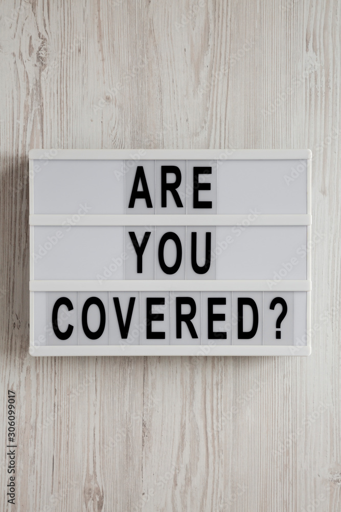 'Are you covered?' words on a modern board on a white wooden surface, top view. Overhead, from above, flat lay. Close-up. 'Are you covered?' words on a modern board on a white wooden surface, top view. Overhead, from above, flat lay. Close-up.