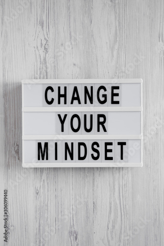 Overhead view, 'Change your mindset' words on a lightbox on a white wooden background. Top view, from above, flat lay.