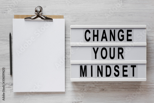 'Change your mindset' words on a modern board, clipboard with blank sheet of paper on a white wooden background, overhead view. Top view, from above, flat lay. photo