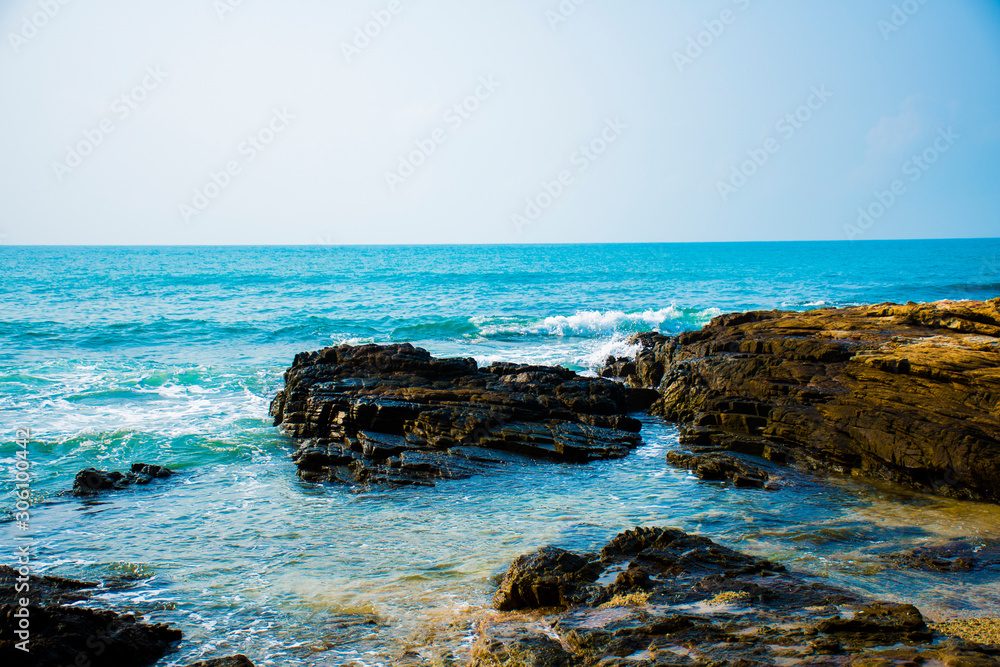 The rocks on the beach and the incoming sea water. And the sea and sky background