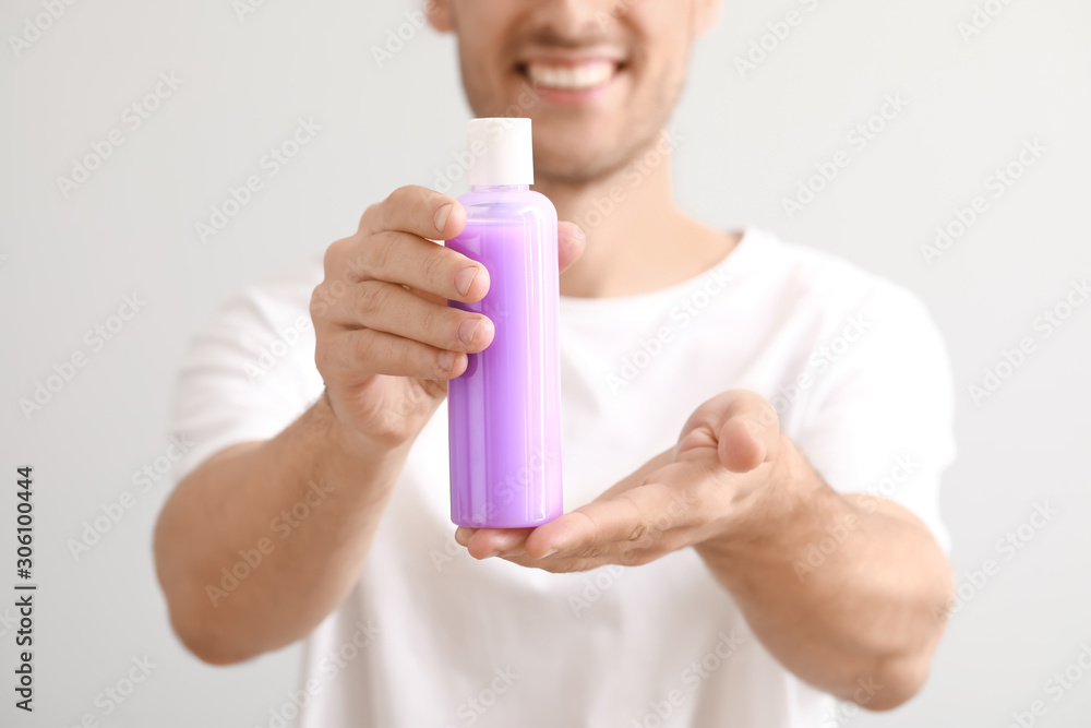Handsome young man with cosmetic product on light background Handsome young man with cosmetic product on light background