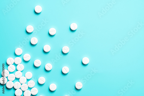 scattered white pills on a blue background. background with pills.