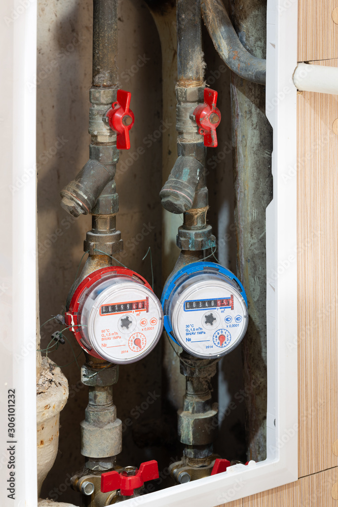 Sealed counters for metering consumption. Hot and cold water meters on pipes with red taps