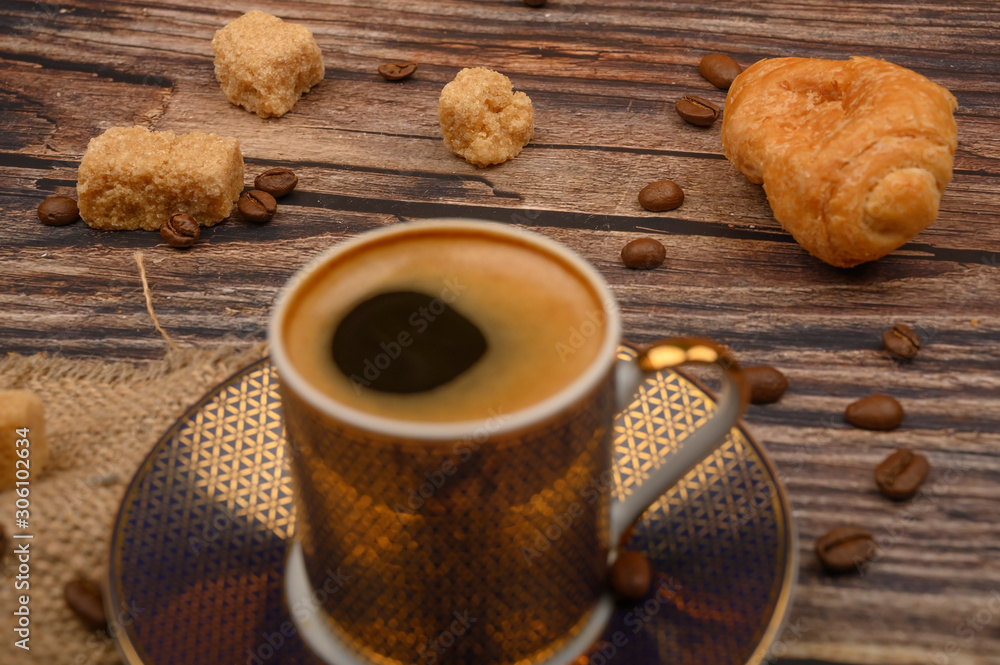 Coffee Cup, croissants, brown sugar and coffee beans on wooden background. Close up. Coffee Cup, croissants, brown sugar and coffee beans on wooden background. Close up.