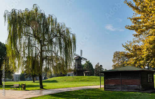 Windmill and blue sky in the background. Silhouette of windmill among greener...