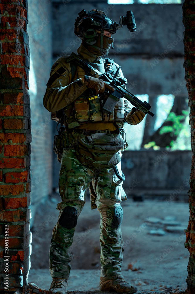 Man in uniform with machine gun and night-vision device inside broken building. Airsoft soldier in night building, beside two walls. Vertical photo Man in uniform with machine gun and night-vision device inside broken building. Airsoft soldier in night building, beside two walls. Vertical photo