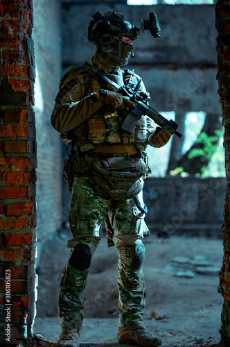 Man in uniform with machine gun and night-vision device inside broken building. Airsoft soldier in night building, beside two walls. Vertical photo © Bohdan Petrushko