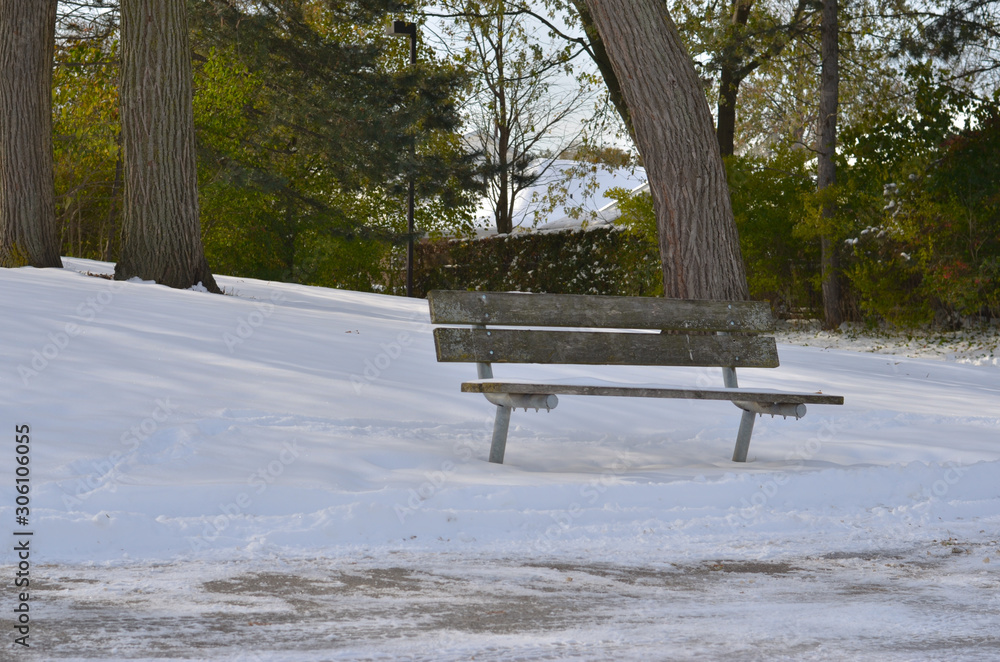 Shot of an Isolated bench in a park covered in fresh first snow of the winter season in North America or Europe. Heavy snowfall is also seen in north indian states of himachal pradesh and uttrakhand