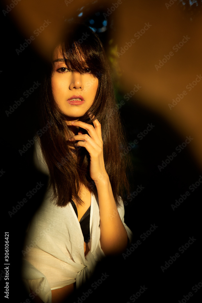 Beautiful young asian woman looking thru dry leaf hole with sunlight shine on face golden hour on trees background. Beautiful young asian woman looking thru dry leaf hole with sunlight shine on face golden hour on trees background.