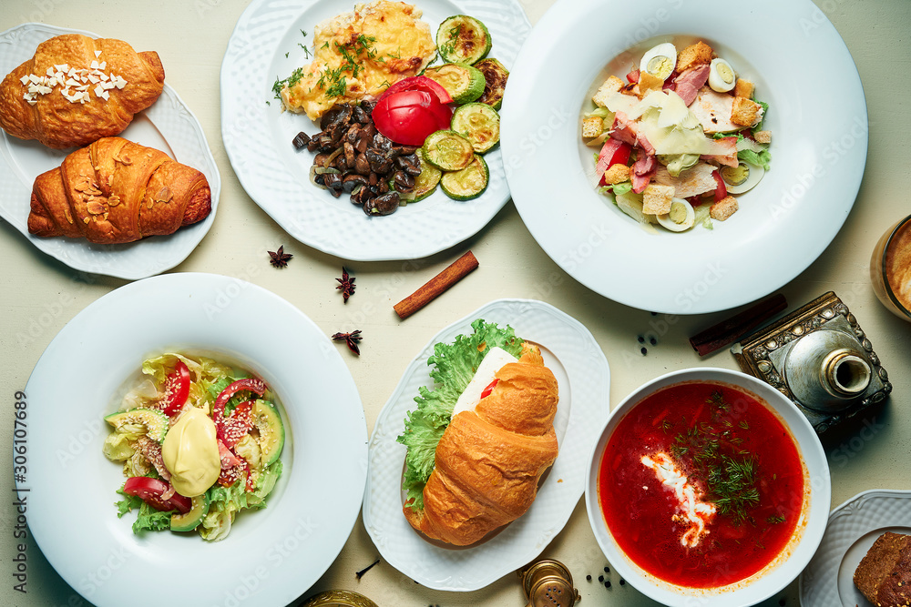 Dining table with a bunch of food. Borsch, salads, croissants for a family dinner. Top view food flat lay. Dining table with a bunch of food. Borsch, salads, croissants for a family dinner. Top view food flat lay.