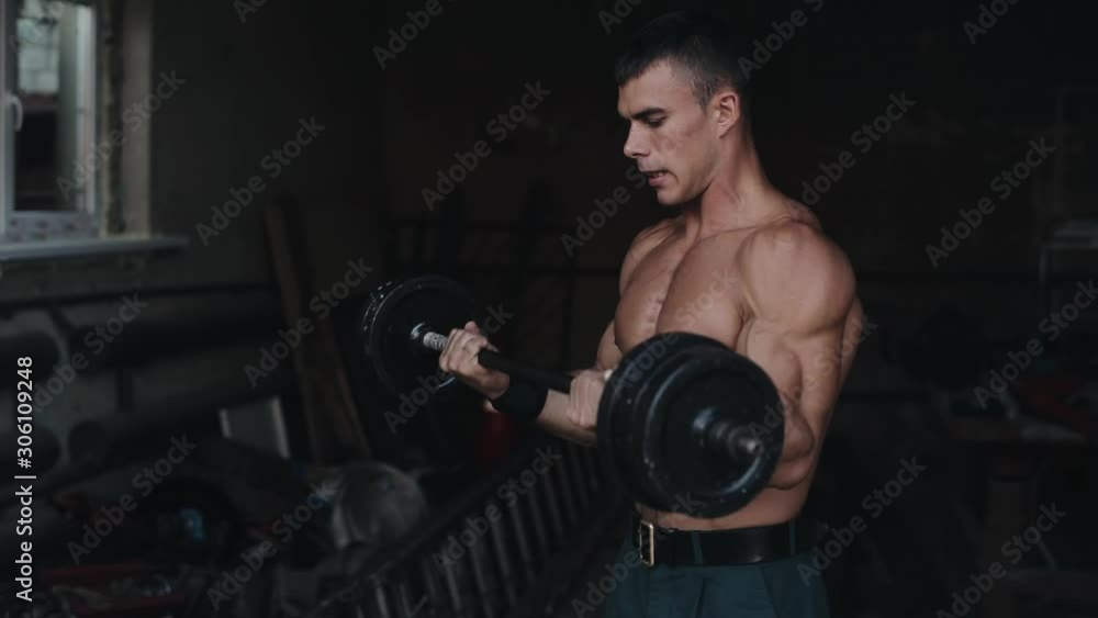 Side view of a strong sportsman lifting a barbell in the gym Side view of a strong sportsman lifting a barbell in the gym