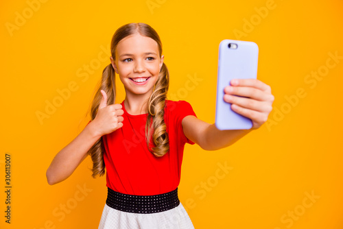 Good job. Photo of pretty small lady holding telephone making selfies raising thumb finger up for blog wear casual red white dress isolated bright yellow color background