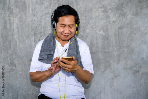 Senior Asian man in sportswear listen to music with smart phone.