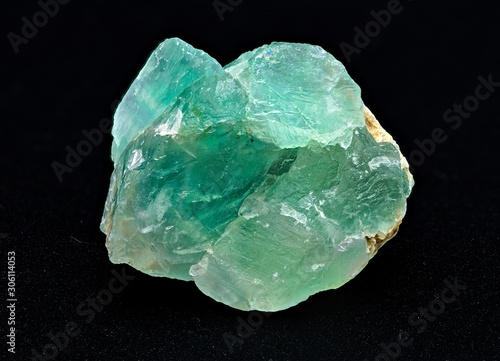Green translucent fluorite rough mineral stone on a black background