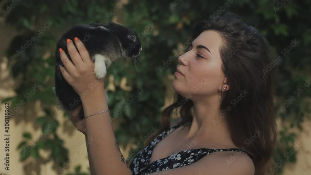 Close view of young beautiful girl hugging little black bunny outdoors Close view of young beautiful girl hugging little black bunny outdoors