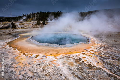 Blue and orange geyser basin with boiling water from geothermal heat.