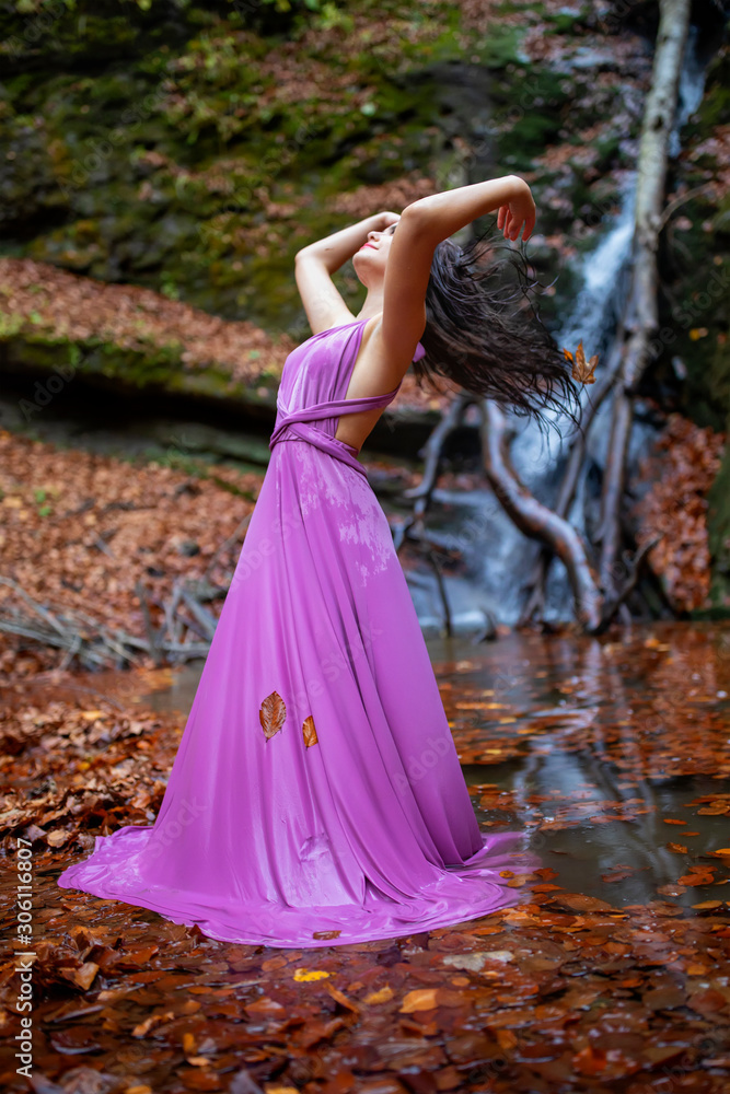 Portrait of a beautiful hispanic young woman near waterfall in autumn season