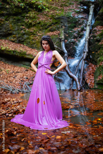 Portrait of a beautiful hispanic young woman near waterfall in autumn season