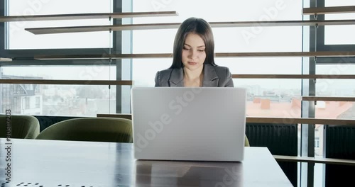 Concerned woman working on laptop computer and looking away thinking solving problem at office. Serious attractive female working with notebook