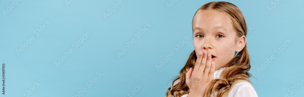 panoramic shot of shocked and cute kid looking at camera and obscuring face isolated on blue panoramic shot of shocked and cute kid looking at camera and obscuring face isolated on blue