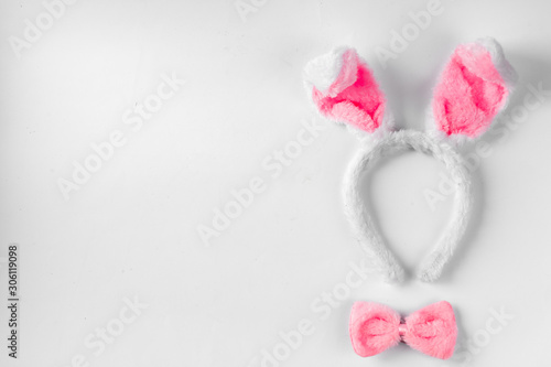 Top view of cute bunny ears with a small pink bow on wooden background.
