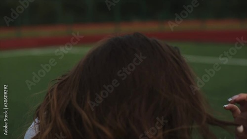 portrait of Beautiful brunette woman inblue sundress sitting on the lawn near a football goal at the stadium. sunlight. A girl with a perfect figure and in great shape. pretty girl in orange photo