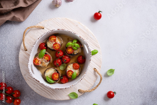 Baked champignon caps stuffed with mozarella, cherry tomatoes and basil. Top view, copy space. Restaurant menu. Healthy nutrition. keto dieting