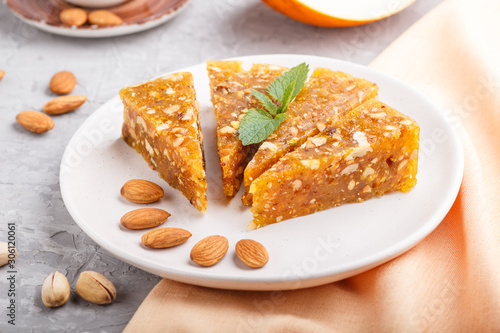 Traditional turkish candy cezerye made from caramelised melon, roasted walnuts, hazelnuts, cashew, pistachios on white ceramic plate and a cup of coffee on a gray concrete background. side view