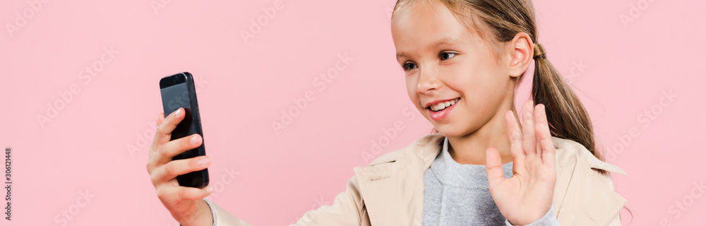 panoramic shot of smiling and cute kid waving during video chat isolated on pink panoramic shot of smiling and cute kid waving during video chat isolated on pink