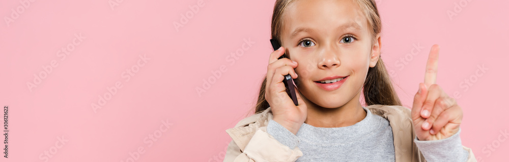 panoramic shot of smiling kid showing idea sign and talking on smartphone isolated on pink panoramic shot of smiling kid showing idea sign and talking on smartphone isolated on pink
