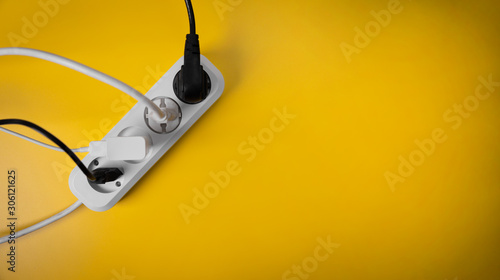 Fotografie electricity consumption - electric extension cord full of power plugs on yellow background with copy space