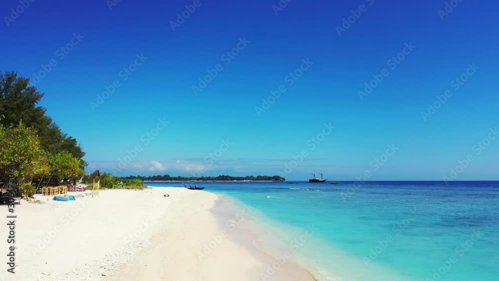 Paradise exotic beach in front of resort located on tropical island with lush vegetation, washed by calm clear turquoise lagoon on a sunny day with bright blue sky Paradise exotic beach in front of resort located on tropical island with lush vegetation, washed by calm clear turquoise lagoon on a sunny day with bright blue sky