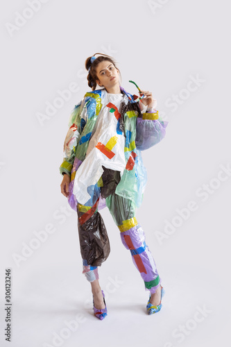 Woman wearing plastic on white background. Female model in clothes and shoes made of garbage. Fashion, style, recycling, eco and environmental concept. Too much pollution, we're eating and taking it.