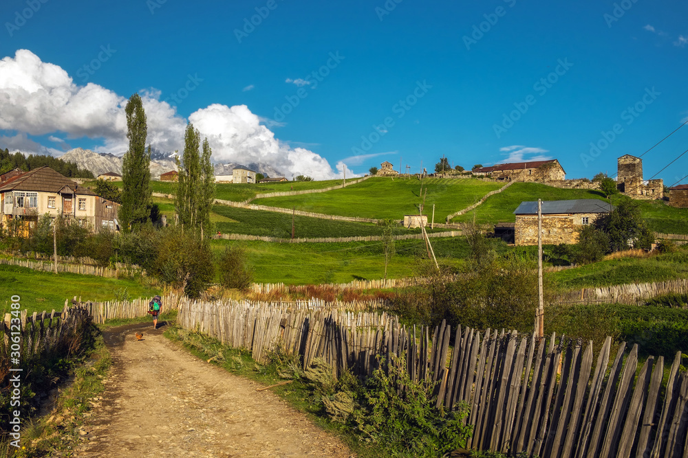 Beautiful summer rural landscape in Svaneti Georgia with pasture fields dirt road and wooden fence
