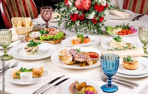 Served for holiday banquet restaurant table with dishes, snack, salads, cutlery, wine and water glasses. European food in a restaurant setting. Table set for an event party. catering