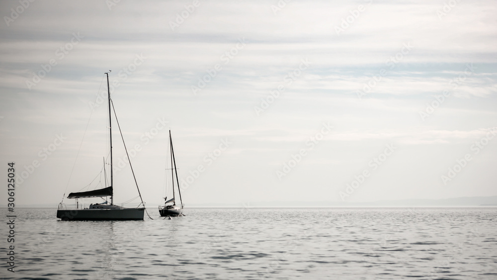 Lake Garda, Italy. A pair of yachts floating gently on the calm waters of the Italian Lake District.