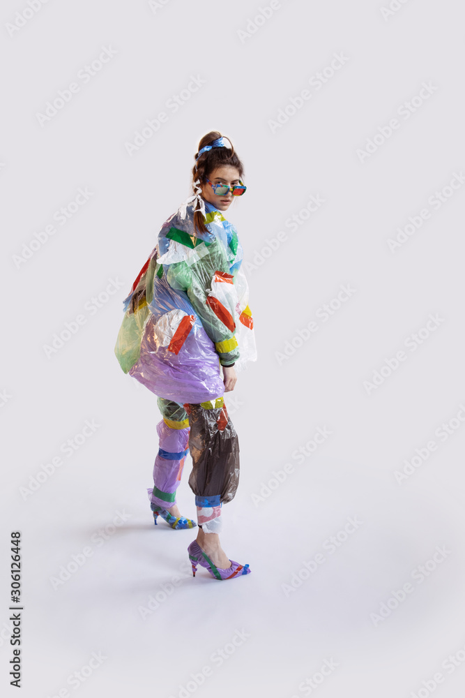 Woman wearing plastic on white background. Female model in clothes and shoes made of garbage. Fashion, style, recycling, eco and environmental concept. Too much pollution, we're eating and taking it. Woman wearing plastic on white background. Female model in clothes and shoes made of garbage. Fashion, style, recycling, eco and environmental concept. Too much pollution, we're eating and taking it.