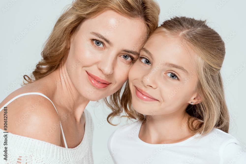 attractive mother and smiling daughter looking at camera isolated on grey attractive mother and smiling daughter looking at camera isolated on grey