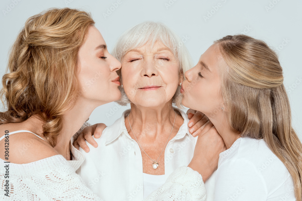 granddaughter and mother kissing grandmother with closed eyes isolated on grey granddaughter and mother kissing grandmother with closed eyes isolated on grey