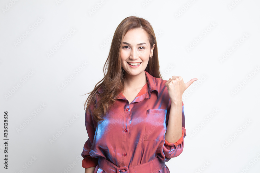 Young Asian woman smile and point to copy space with her thumb. Young Asian woman smile and point to copy space with her thumb.