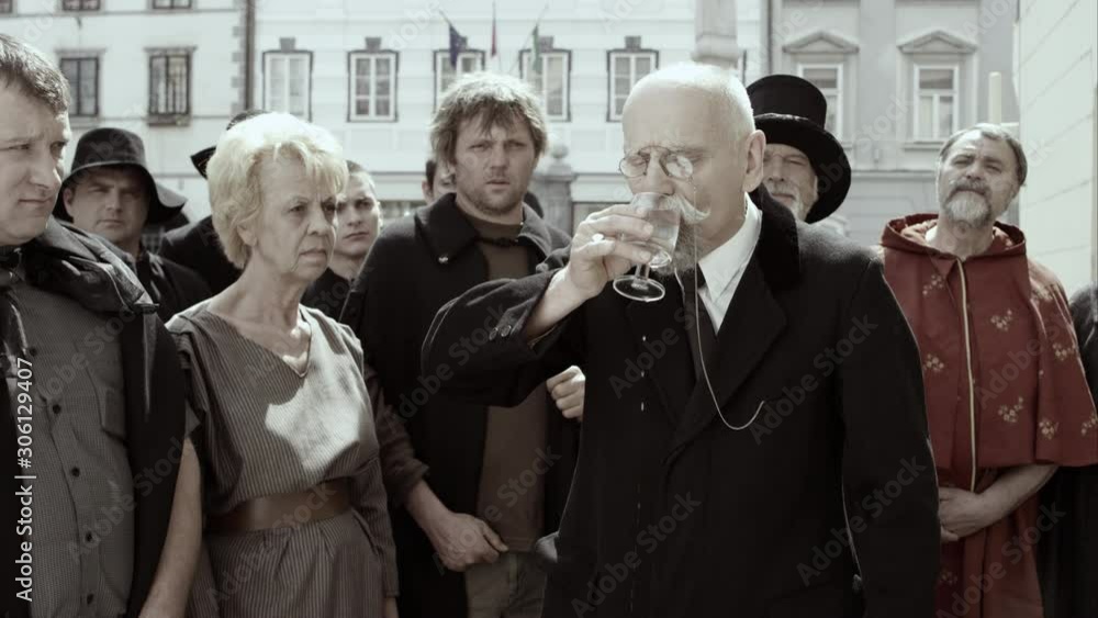 Crowd Watches Attentively As Older Man Drinks Clear Liquid From Glass Crowd Watches Attentively As Older Man Drinks Clear Liquid From Glass