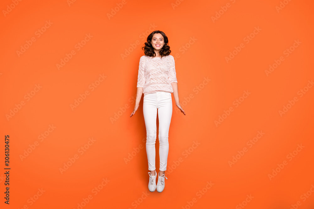 Full length photo of positive cheerful girl have spring time holidays jump enjoy content emotions wear casual style outfit sneakers isolated over orange color background