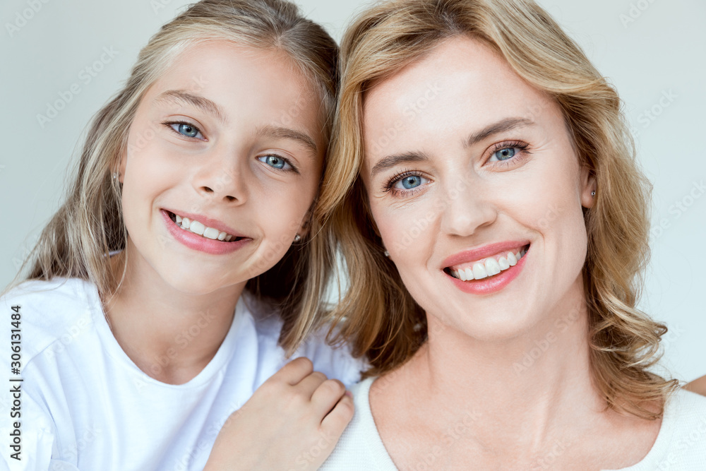 attractive mother and smiling daughter looking at camera isolated on grey attractive mother and smiling daughter looking at camera isolated on grey